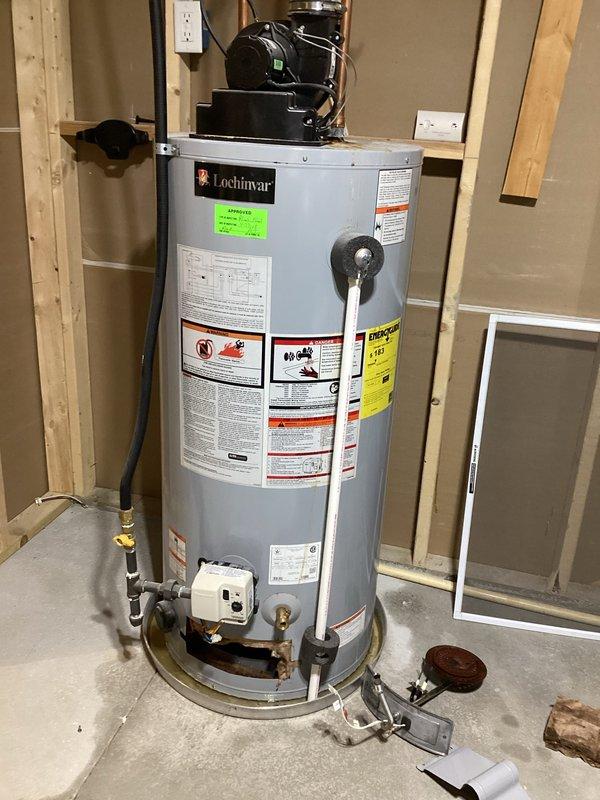 # Water Heater Replacement

Removed and replaced failed residential water heater system. Disconnected existing unit including all water supply lines, gas connections, and venting components. Installed new Lochinvar high-efficiency water heater with proper clearances per manufacturer specifications. Connected copper supply piping with brass fittings and installed code-compliant drain pan beneath unit. Secured black pump/motor assembly at top of tank and verified all plumbing connections for leaks. Tested temperature and pressure relief valve operation. Verified proper gas flow and ignition sequence. System commissioned and operational upon completion.