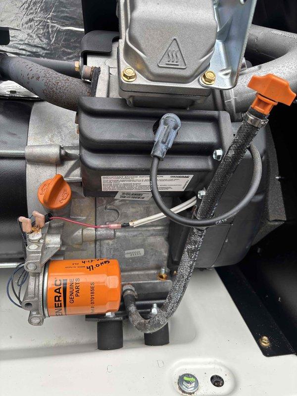 # Generator Preventive Maintenance Service

Performed scheduled preventive maintenance and tune-up on residential standby generator unit. Accessed exterior-mounted generator compartment and conducted comprehensive inspection of all major components including air handling system, electrical connections, and fuel delivery system.

Inspected and verified proper operation of blower assembly and ductwork within the black housing unit. Examined electrical panel connections and warning labels for compliance and visibility. Verified integrity of metallic insulation material in upper compartment section.

Evaluated fuel system components including orange-colored pump assembly and associated piping at base of unit. Inspected FRAM genuine parts oil filter and connected hoses for proper installation and condition. Checked all brass mounting hardware and securing bolts for tightness. Examined multiple connection points, orange protective caps, and black insulated tubing throughout the system for we