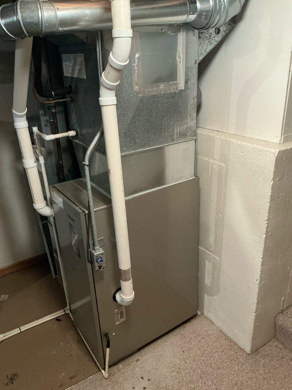 Completed furnace replacement estimate for single-family residence with 20-year-old Carrier Performance 93 unit that has reached end of service life. Assessed existing basement installation including current ductwork, PVC venting system, and clearance requirements for new equipment. Documented existing system configuration with water heater proximity, concrete block construction, and available utility connections to provide accurate replacement specifications for new high-efficiency furnace installation.