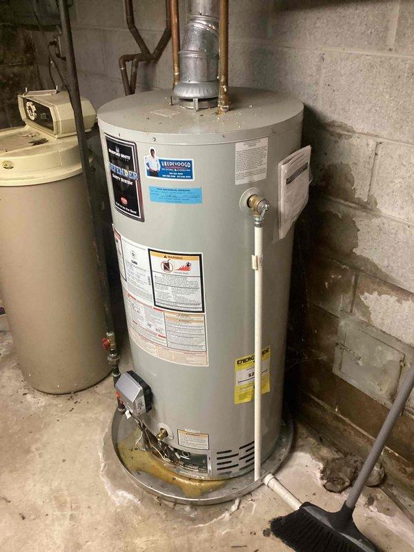 Conducted water heater replacement estimate at residential property. Inspected existing gas-fired water heater in basement utility area, noting visible moisture staining and discoloration on tank base and surrounding concrete floor indicating potential leak or condensation issues. Evaluated unit's condition, plumbing connections, venting system, and clearance requirements. Documented equipment specifications and existing installation configuration including copper supply lines, pressure relief valve, and metal flue venting. Provided replacement options and recommendations for new water heater installation.