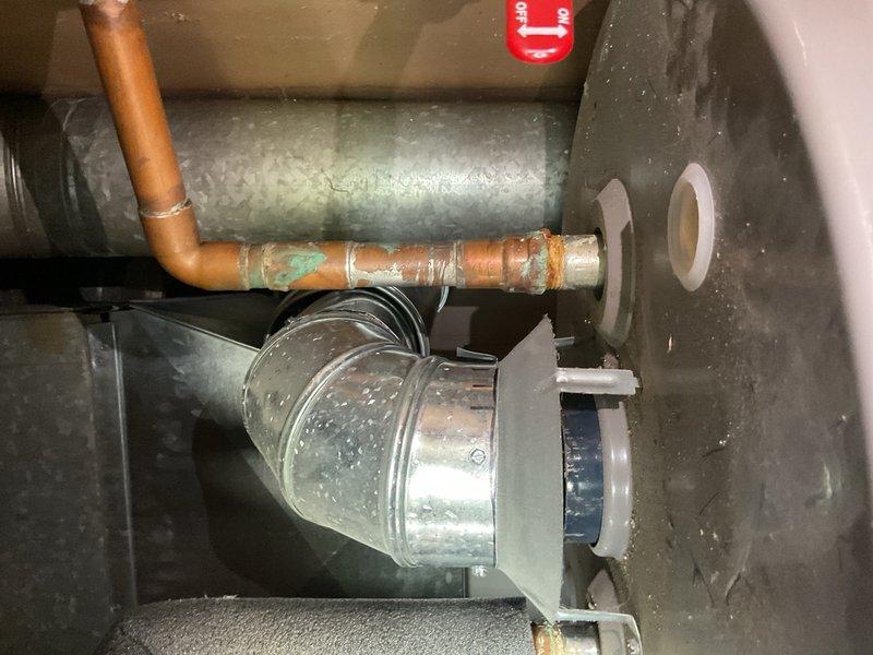 Completed estimate for water heater replacement in mechanical room. Inspected existing HVAC ductwork and water heater installation area, documenting current conditions including galvanized ductwork with 90-degree elbow joints, copper piping showing corrosion and patina, and condensation present on cylindrical air handler components. Photographed utility space configuration, electrical wiring routing, and structural support systems to provide comprehensive assessment for water heater installation requirements and clearance specifications.