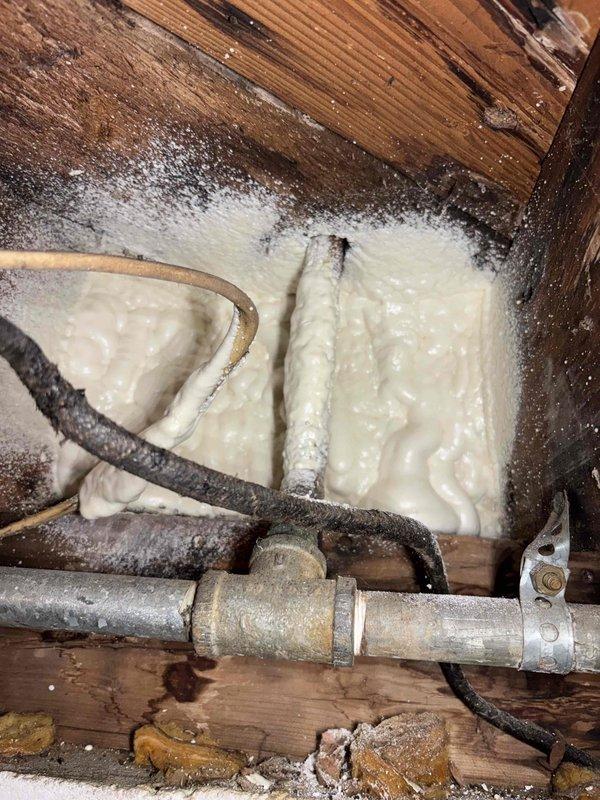 Responded to service call for reported boiler leak on 1-year-old Utica WT 2-2030 unit. Upon inspection, located leak source at corroded pipe connection in crawl space area adjacent to boiler installation. Identified moisture damage and discoloration on surrounding wooden framing members and compromised fiberglass insulation from water exposure. Assessed threaded pipe connections and galvanized steel piping showing surface corrosion and deterioration. Documented conditions with photographs showing affected plumbing infrastructure, spray foam insulation areas, and copper piping with visible oxidation. Addressed leak at connection point and verified system integrity upon completion.