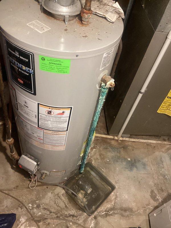 Conducted on-site evaluation of residential water heater system and documented current equipment condition. Inspection revealed an A.O. Smith automatic storage water heater with significant corrosion on pressure relief discharge piping, exhibiting green and white oxidation buildup and mineral deposits. Unit positioned in basement utility area with drain pan present beneath tank. Photographed manufacturer labels, safety warnings, AHRI certification markings, and all visible plumbing connections including copper supply lines and brass fittings at top of unit. Documented floor conditions showing water staining and mineral deposits around base of equipment, indicating potential historical discharge or seepage. Provided comprehensive estimate for water heater replacement options based on observed equipment age, corrosion severity, and current operating condition.