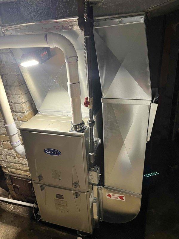 Completed full installation of Carrier brand furnace unit in basement utility space. System was mounted against masonry wall with proper clearances, connected to existing ductwork distribution system, and equipped with white PVC venting and condensate drainage piping routed vertically through ceiling. All gas line connections, electrical wiring, and safety controls were installed per manufacturer specifications and local code requirements, with system tested and verified operational upon completion.