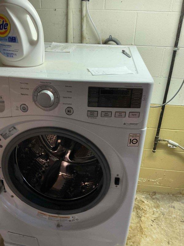 Responded to water leak call in front of washing machine, initially suspected to be from humidifier line. Upon inspection, examined LG front-loading washer and surrounding area, including drainage connections and hose routing along wall. Photographed washing machine interior drum and exterior installation to document condition and identify potential leak source.