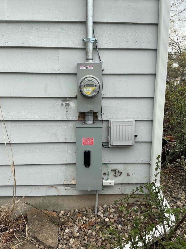 Completed 200-amp electrical service upgrade at residential property. Coordinated utility company power disconnect and reconnect to safely replace exterior meter base, weatherhead assembly, and main service panel. Installed new gray metal meter socket and breaker panel enclosure on exterior wall with proper conduit runs and grounding. Upgraded interior breaker panel with modern circuit breakers, main disconnect, and circuit labeling for all branch circuits including HVAC and general lighting loads. All work performed under electrical permit and passed final inspection.