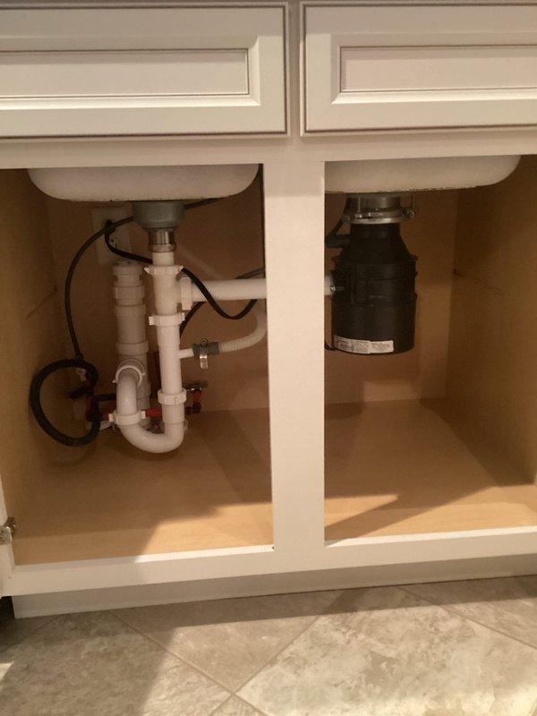 Provided project estimate for kitchen plumbing upgrades including replacement of existing sink with new 16-gauge stainless steel undermount model (RUVATI RVM4200), installation of new faucet assembly, and replacement of existing garbage disposal unit. Assessed current under-sink plumbing configuration featuring white PVC drain lines with P-trap, water supply lines, and mounting requirements for new fixtures on granite countertop surface.