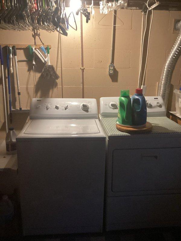 Completed estimate for installation of washer and dryer hookups on the upper level of a 1955-built residence. Assessed existing basement plumbing infrastructure, including PVC drain lines and venting system along concrete block walls, and documented current laundry appliance configuration to determine scope of work for relocating water supply lines, drain connections, and venting required for second-floor installation.
