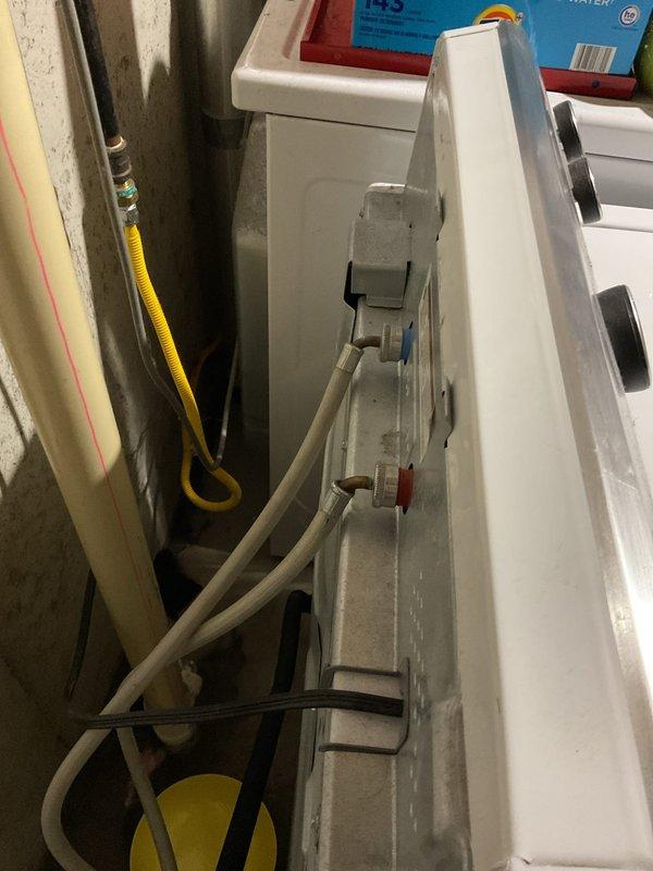 Responded to washing machine hot water supply line leak at connection point. Upon arrival, found the hot water hose connection to the washing machine actively dripping despite the shut-off valve being closed. Inspected the copper supply lines with shut-off valves (black and blue handled) and PEX connections in the utility area. Identified failed rubber washer and improper seal at the hose-to-machine connection as the source of the leak. Replaced the supply hose with new braided stainless steel washing machine connector, ensuring proper gasket installation and secure threading at both the valve outlet and machine inlet. Verified shut-off valves were functioning correctly and holding pressure when closed. Restored water supply and tested connections under full pressure to confirm leak was eliminated. Photographed existing plumbing infrastructure including copper supply lines, shut-off valves, and PEX tubing installation for service records. All connections secure with no active leaks upo