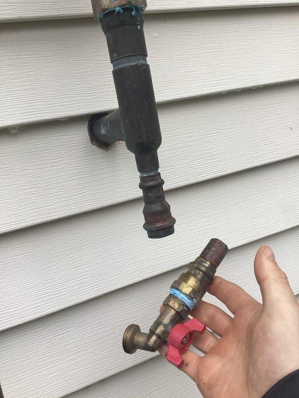 Responded to service call regarding sprinkler supply line ball valve that was not replaced during previous visit. Upon inspection, found portion of sprinkler water supply system disconnected but confirmed no active leaking present. Documented existing conditions showing weathered vertical black pipe connected to oxidized copper piping with brass valve assembly featuring red wheel-style gate valve handle. System components displayed typical outdoor weathering with visible corrosion at connection points and patination on copper sections. Photographed current installation mounted on exterior siding for reference and communicated findings to team for customer follow-up as requested.