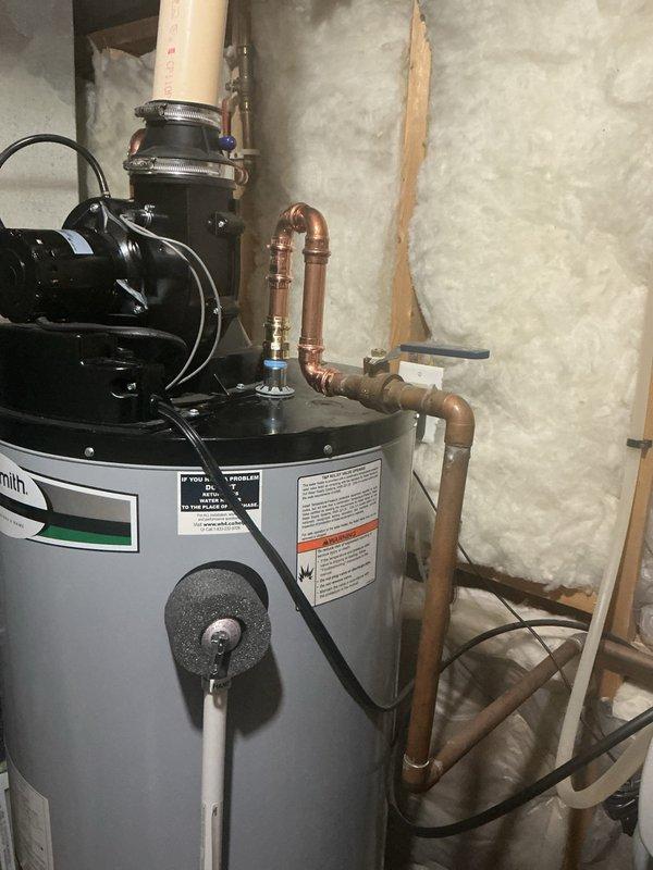 Responded to water heater service call for 4-year-old A.O. Smith unit showing corrosion on top assembly. Upon inspection, confirmed water heater was operational but found corrosion present on top connections and fittings requiring cleaning and repair. Documented existing conditions with photos showing copper piping connections, top-mounted pump assembly with black hoses, and overall installation in utility area. Coordinated with authorized representative regarding necessary corrective measures to address corrosion issues and prevent further deterioration of connections.