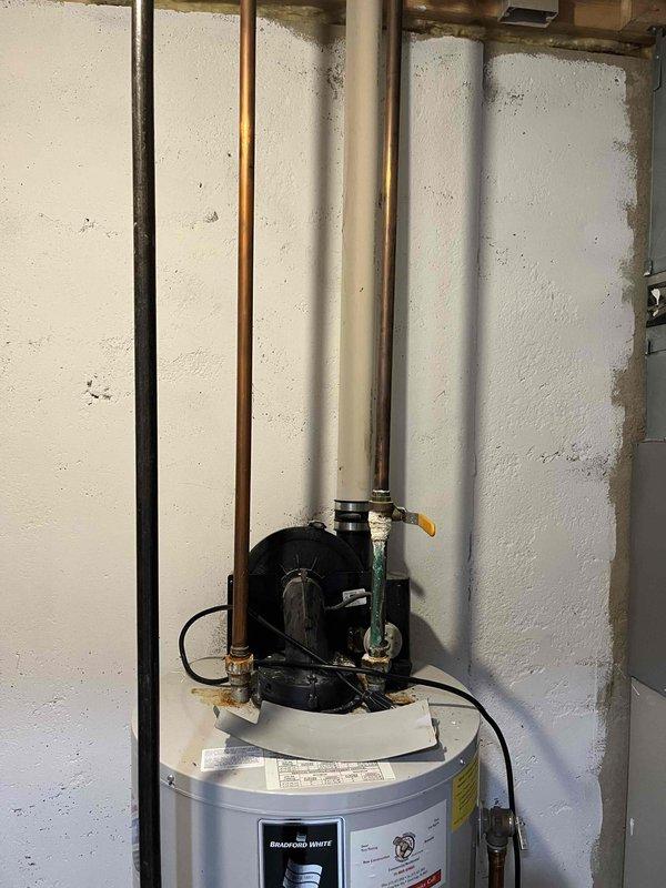 Completed estimate for replacement of 20-year-old Bradford White residential water heater located in basement utility area. Unit was installed in 2006 and has been drained by homeowner in preparation for replacement. Existing installation includes standard plumbing connections with copper supply lines, gas line with brass fittings, blue-handled shutoff valve, drainage pan, and circulator pump assembly mounted on top of unit. Documented current configuration and measurements for replacement specifications.