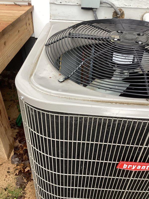Responded to service call for Bryant air conditioning condenser unit damaged by falling ice from roof. Upon inspection, confirmed exterior cabinet housing was bent inward sufficiently to cause fan blade interference with metal grille during operation. Assessed structural integrity of condenser cabinet and fan assembly. Carefully reshaped and straightened damaged cabinet section to restore proper clearance between fan blades and housing. Verified fan rotation without obstruction and confirmed adequate clearance throughout full range of motion. Inspected electrical connections, conduit, and junction box for any secondary damage from impact. Unit returned to safe operational condition with no blade contact or mechanical interference detected.