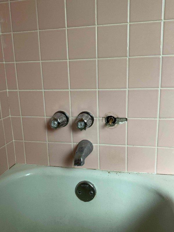 Responded to a quoted repair request for a deteriorating triple-handle shower valve assembly in a vintage bathroom with pink tile and mint green bathtub. Replaced the compromised right-side valve handle and trim, which exhibited exposed mounting hardware, damaged surrounding tile, and deteriorated grout and caulking. Restored proper function to the three-handle tub/shower configuration and addressed cosmetic damage to maintain water-tight integrity of the installation.