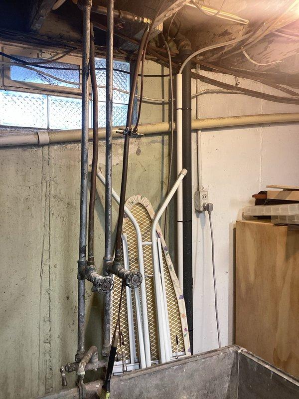 Conducted on-site evaluation for water softener installation in a 60-year-old residential property. Assessed existing plumbing infrastructure in basement utility area, documenting current pipe configuration including vertical supply lines and horizontal distribution system. Evaluated installation location near existing plumbing network with multiple pipe connections and fittings. Photographed workspace conditions and plumbing layout to determine equipment placement, connection points, and any modifications required for proper water softener integration into the home's water supply system.