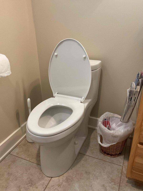 Responded to plumbing leak complaint occurring in basement when upstairs toilet was flushed. Conducted visual inspection of upstairs toilet and surrounding fixtures to identify source of water intrusion. Documented bathroom conditions and toilet installation with photographic evidence for service records, noting standard two-piece toilet configuration with raised lid position during diagnostic assessment.