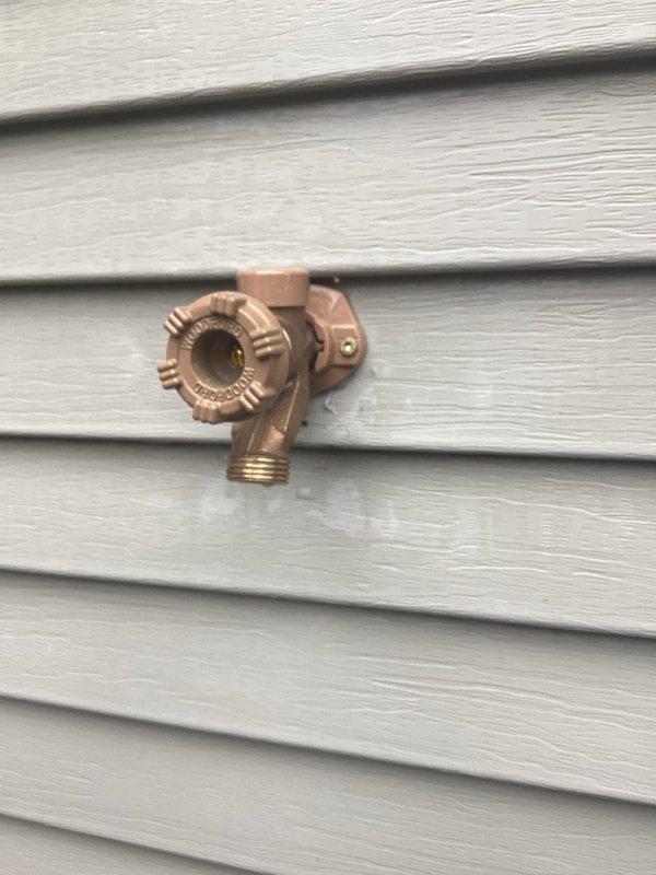Responded to callback for outdoor hose bib that was previously repaired but continued to leak after being turned on for the season. Inspected brass spigot mounted on exterior vinyl siding and identified persistent leak issue. Performed necessary repairs to address the ongoing water seepage from the fixture, ensuring proper seal and function of the cross-handle valve assembly and threaded outlet connection.