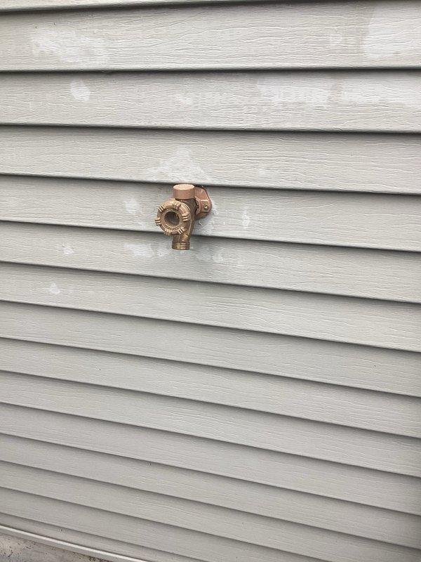 Responded to callback for outdoor hose bib that was previously repaired but continued to leak after being turned on for the season. Inspected brass spigot mounted on exterior vinyl siding and identified persistent leak issue. Performed necessary repairs to address the ongoing water seepage from the fixture, ensuring proper seal and function of the cross-handle valve assembly and threaded outlet connection.