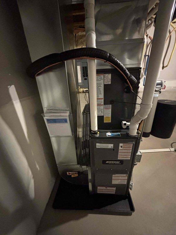 Completed full HVAC system installation including new furnace and air conditioning unit in residential basement utility area. Installed furnace on protective mat with proper clearances, connected flexible ductwork, and ran white PVC venting per manufacturer specifications. Performed refrigerant charging and pressure testing using manifold gauges to verify proper system operation and refrigerant levels within acceptable parameters.