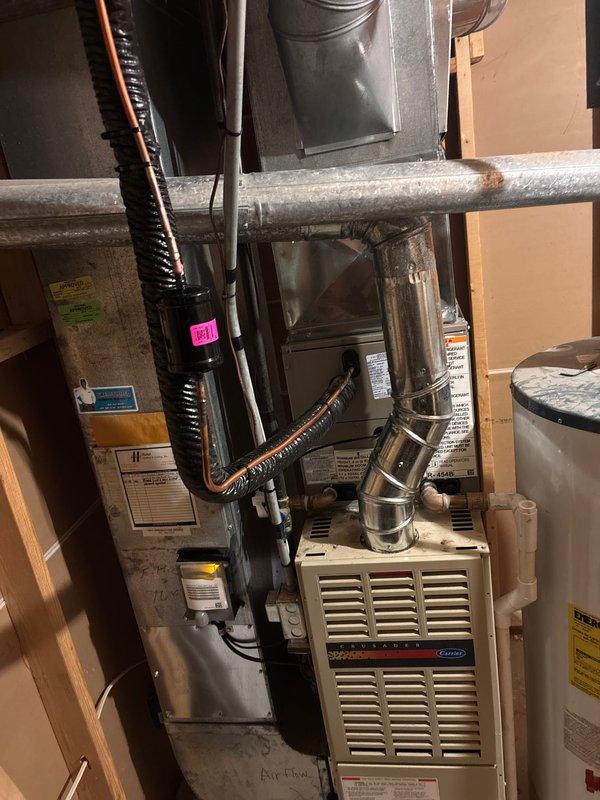 Completed full HVAC system installation in residential basement utility room, including new Carrier furnace unit and air conditioning system with associated ductwork and refrigerant lines. Installed silver flexible ductwork, insulated supply lines, and black refrigerant line sets with proper insulation wrapping. All components properly secured, labeled, and tested for operational functionality. System commissioned and verified for proper airflow and refrigerant charge levels.