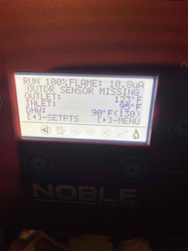 Responded to service call for 7-year-old Lochinvar Noble fire tube boiler experiencing lockout conditions and loss of flame resulting in no hot water production. Upon arrival, system had been reset and was operational but displaying "OUTDOOR SENSOR MISSING" error on control panel. Documented system operation showing flame signal readings fluctuating between 10.8μA and 18.6μA, with outlet temperatures ranging from 123°F to 142°F against 180°F setpoint, inlet temperatures between 95°F and 138°F, and DHW temperatures at 90-111°F. System running at 100% fire rate attempting to satisfy temperature demand, indicating potential issues with flame sensor signal strength and missing outdoor reset sensor affecting proper modulation and system efficiency.