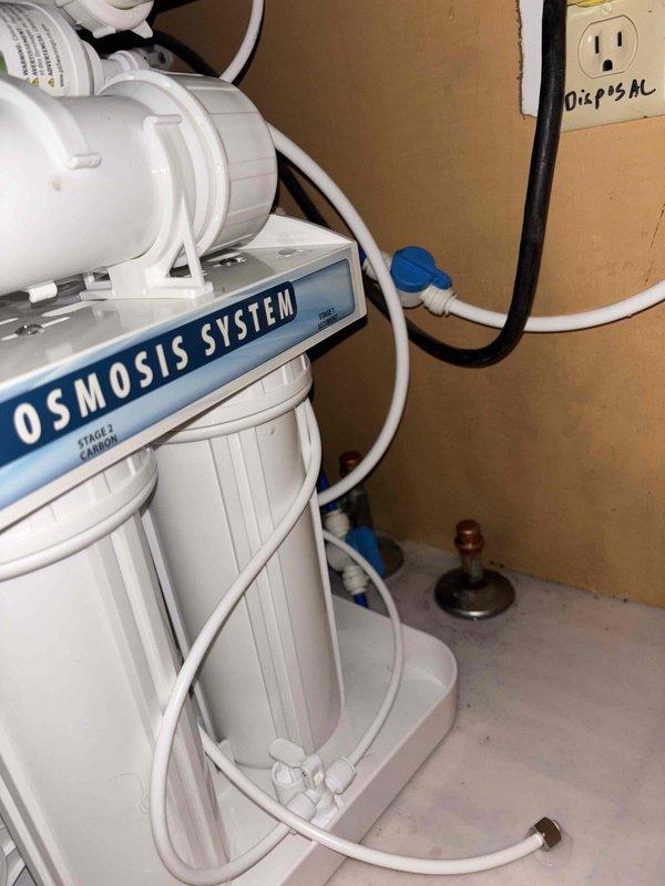 Installed a 4-stage reverse osmosis water filtration system in utility area, including mounting the unit to wall, connecting supply and drain lines, and establishing electrical connection. System was tested and verified operational with all filter cartridges properly seated and tubing secured.