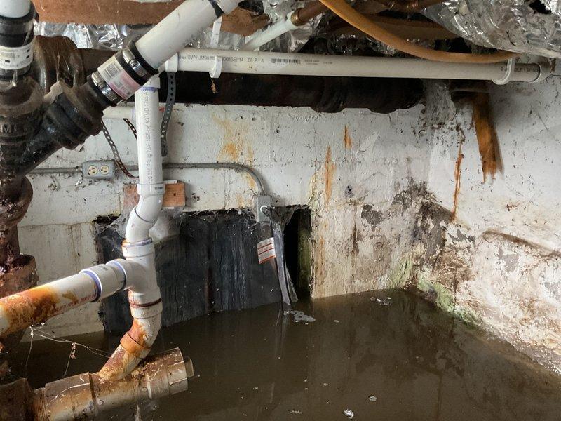 Responded to emergency water leak in crawlspace with active flooding and standing water throughout the space. Upon arrival, discovered severely corroded metal piping with compromised integrity and extensive rust damage, along with deteriorated plumbing infrastructure showing signs of recent disturbance potentially related to prior plumbing work. Documented extensive water damage to concrete block walls including rust staining, mold growth, and moisture intrusion patterns indicating prolonged exposure. Assessed PVC and metal piping systems, noting advanced corrosion on metal pipes and multiple connection points requiring attention. Photographed conditions for insurance documentation and recommended immediate water extraction, pipe repair or replacement of corroded sections, mold remediation, and structural assessment of water-damaged walls.