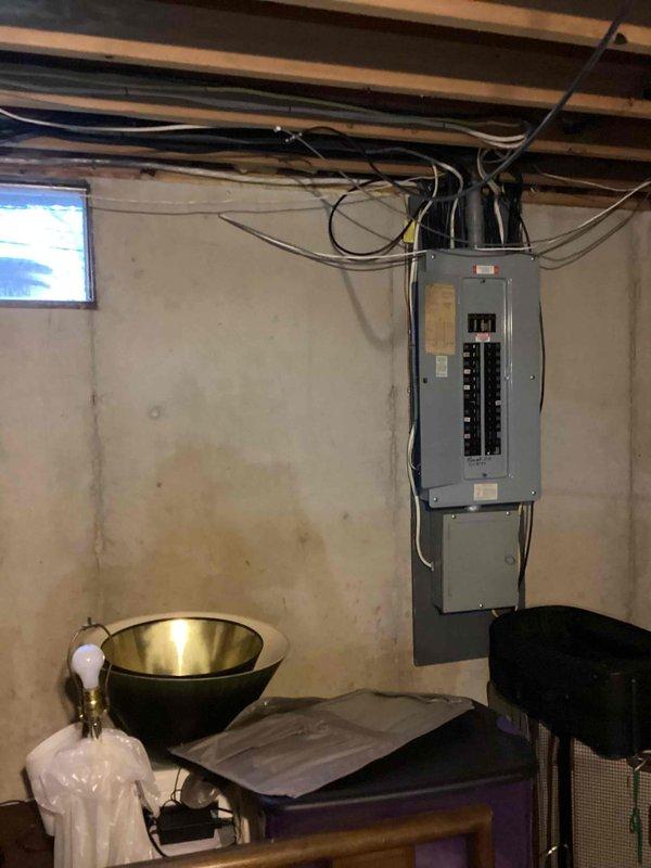 Conducted on-site evaluation for standby generator installation at residential property. Assessed existing electrical service panel configuration, photographed 200-amp main breaker panel with dual-column circuit breaker arrangement to determine load capacity and transfer switch integration requirements. Documented basement utility area conditions including available space for generator transfer switch installation, concrete block wall structure, and existing electrical conduit pathways. Evaluated panel accessibility and determined optimal routing for generator feed cables from exterior pad location to transfer equipment. Prepared comprehensive estimate for automatic standby generator system including equipment specifications, transfer switch requirements, and installation scope.