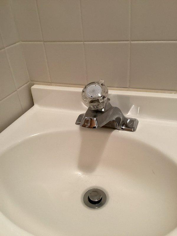 Completed installation of new chrome single-handle bathroom faucet with matching pop-up drain assembly on white porcelain sink. Removed existing two-handle faucet fixture, installed replacement unit, connected hot and cold water supply lines, tested for proper operation and leaks, and verified drainage system functionality.