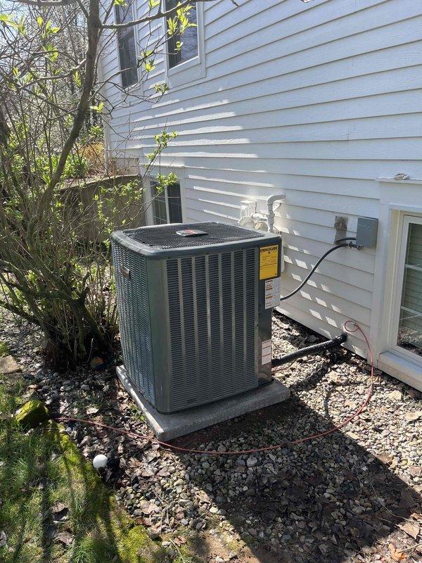 Completed full HVAC system installation including indoor air handler and Carrier furnace unit mounted vertically in mechanical closet with proper refrigerant line connections, PVC condensate drainage, and ductwork integration. Installed outdoor condenser unit on gravel pad against exterior wall with secure mounting, proper electrical conduit routing, and refrigerant line connections to house. All equipment tested and operational, with manufacturer labels visible and installation meeting code requirements for residential HVAC systems.