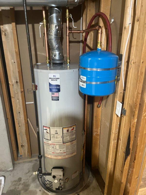 Successfully completed a full HVAC system replacement and water heater installation in the basement utility area. Removed existing air conditioning system and installed new black furnace unit with metallic supply and return ductwork, properly secured between wall studs with all ventilation and safety labels visible. Installed new Bradford White residential water heater with copper supply lines, brass shut-off valves, and blue thermal expansion tank mounted to the side with proper pressure relief connections. All plumbing connections completed with code-compliant materials, electrical conduit run for power supply, and exhaust venting installed per manufacturer specifications. System tested and verified operational upon completion.