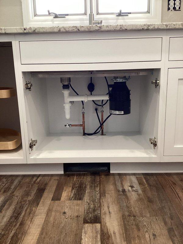 Completed installation of new kitchen plumbing fixtures including double-basin stainless steel sink with modern brushed stainless steel high-arc faucet, garbage disposal unit, and dishwasher connections. All plumbing connections secured with proper PVC drainage piping and supply lines installed per code, with system tested and verified leak-free upon completion.