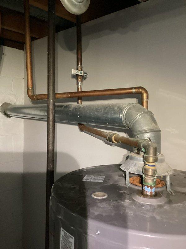 Responded to no heat call where water heater was actively spraying water onto furnace equipment. Upon arrival, confirmed water leak originating from water heater tank affecting nearby HVAC system. Observed red indicator light illuminated on furnace control board, likely due to water intrusion from leaking water heater. Documented conditions with photos showing water heater installation, copper and PVC piping connections, and proximity to furnace unit in basement utility space. Advised customer that water heater requires immediate replacement and furnace control board may need evaluation once water source is eliminated.