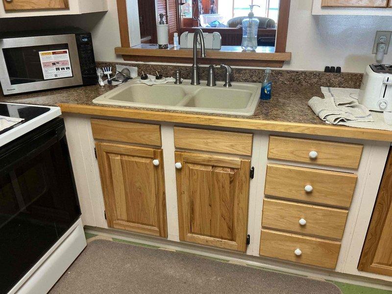 Cabled kitchen sink drain line to clear obstruction and replaced two basket strainers in double-basin sink. Drain system restored to proper operation with no leaks detected upon completion.