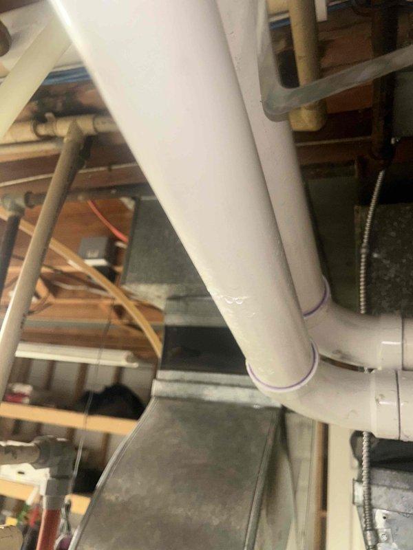 Responded to water heater leak call and conducted thorough inspection of the unit and surrounding plumbing infrastructure. Upon examination of the basement mechanical area, documented the HVAC system, water heater installation, and associated PVC drainage piping network. Photographed the condensate drainage system, including multiple PVC pipes with proper fittings and connections running to the main drain line. Inspected all visible plumbing components, pipe connections, and mechanical equipment for signs of active leakage or moisture damage. System evaluation completed with photographic documentation of current installation conditions for service records.