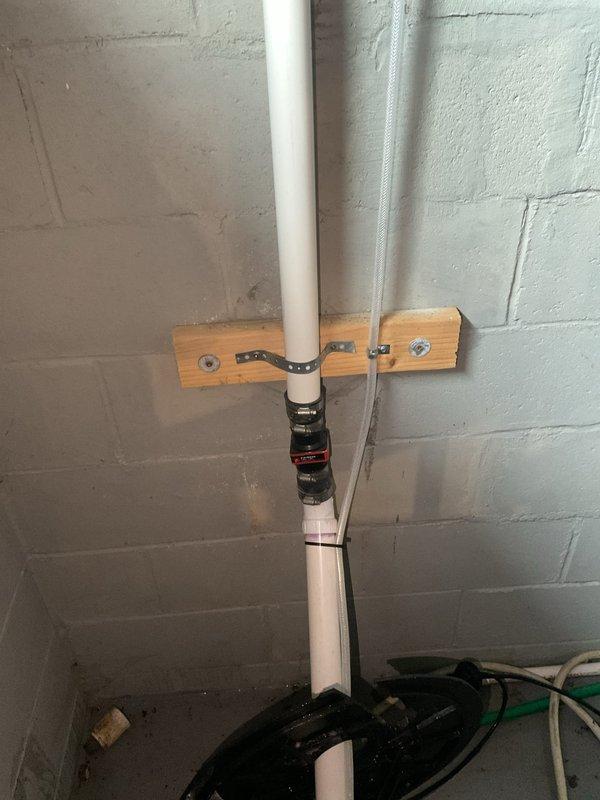 Responded to sump pump failure and performed complete replacement of failed unit. Removed defective sump pump from basin and installed new pump assembly with proper discharge connections. Secured discharge piping using appropriate PVC mounting brackets and strapping to concrete block wall, ensuring proper vertical alignment and support. Connected green discharge hose to pump outlet and verified all electrical connections were properly routed and secured along existing pipe infrastructure using cable ties. Tested new pump operation to confirm proper function and drainage capability upon completion.