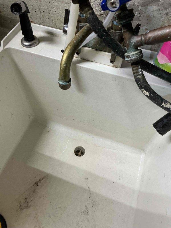 Responded to slow-draining laundry tub sink complaint and performed diagnostic evaluation of the drainage system. Upon inspection, identified debris and sediment accumulation in the basin and drain assembly. Cleared obstruction from the drain line, restored proper water flow, and verified drainage system was functioning correctly before completing the service call.