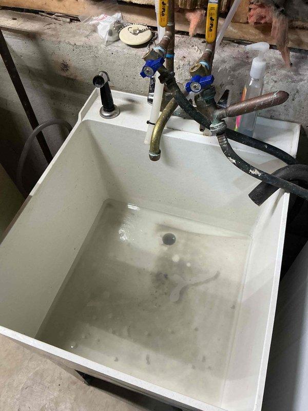 Responded to slow-draining laundry tub sink complaint and performed diagnostic evaluation of the drainage system. Upon inspection, identified debris and sediment accumulation in the basin and drain assembly. Cleared obstruction from the drain line, restored proper water flow, and verified drainage system was functioning correctly before completing the service call.