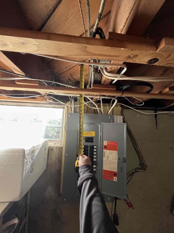 Conducted on-site evaluation for new air conditioning system installation in residential property without existing HVAC equipment. Assessed electrical service capacity and panel configuration in basement utility area, documented existing 200-amp service with available breaker spaces for new AC equipment connection. Photographed electrical infrastructure and measured clearances around service panels to determine equipment placement requirements and verify adequate space for installation of condensing unit, air handler, and associated electrical disconnects per code requirements.