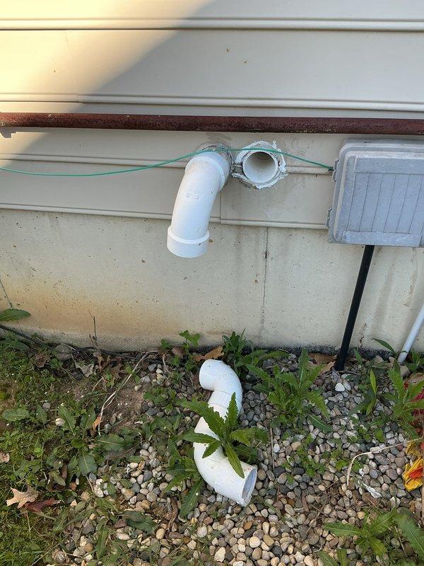 Responded to furnace rattling noise complaint on 11-year-old Goodman unit. Upon inspection, discovered disconnected condensate drain line at exterior termination point. The white PVC drain pipe had separated from the wall-mounted elbow joint, causing vibration and rattling sounds to transmit through the drainage system when the furnace operated. Reconnected and secured the condensate drain line, ensuring proper drainage flow and eliminating the noise issue. System tested and operating quietly.