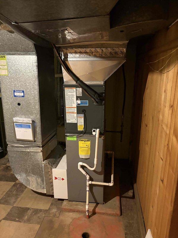 Successfully completed full air conditioning system installation including outdoor condenser unit and indoor air handler. Condenser was positioned on concrete pad adjacent to building exterior with proper refrigerant line routing, electrical disconnect installation, and secure mounting of all components. Indoor air handler was installed in basement mechanical room alongside existing HVAC equipment with black flexible ductwork connections, PVC condensate drain line, and all required electrical connections completed per manufacturer specifications.
