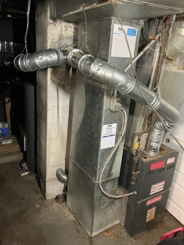 Installed new metallic chimney liner system in residential basement. Routed corrugated flexible duct from existing heating unit through masonry structure, securing proper connection points and ensuring code-compliant venting for HVAC system alongside existing Goodman furnace installation.