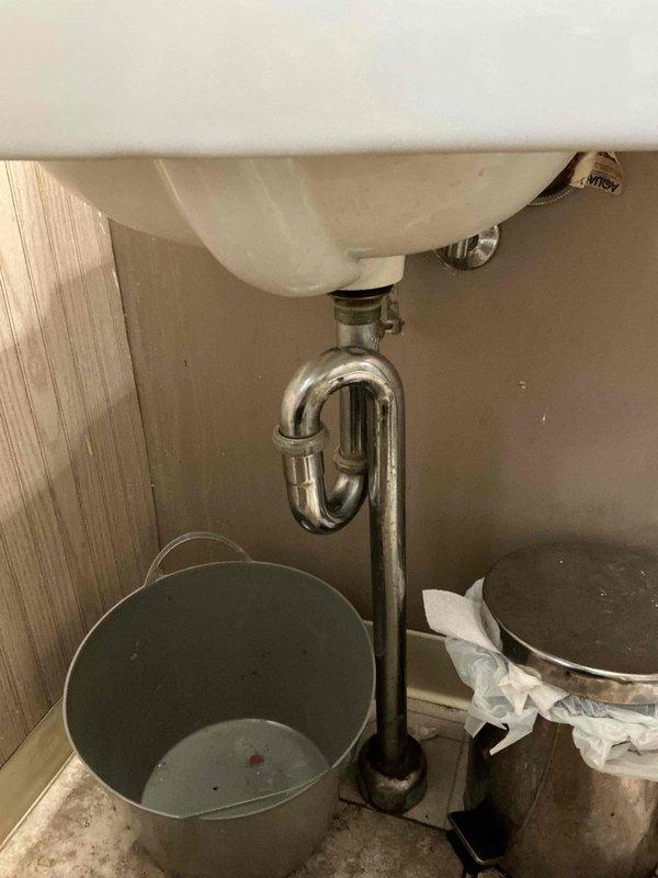 Responded to plumbing leak under bathroom sink that had been active for one day. Upon inspection, identified leak at P-trap connection beneath wall-mounted sink. Tightened drain fittings and verified all connections were properly sealed to stop water drip. Tested system by running water through sink and confirmed leak was resolved with no further dripping present.
