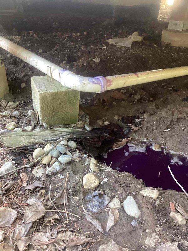 Responded to emergency plumbing leak in crawl space where broken elbow joint between two pipes was actively spraying water near the foundation. Upon arrival, assessed the damaged connection and shut off water supply to stop active spray. Removed failed elbow fitting and cleaned pipe ends of debris and old primer. Installed new PVC elbow joint with proper purple primer and solvent cement application, ensuring secure watertight connections on both pipe ends. Verified repair integrity by restoring water pressure and inspecting for leaks. Placed river rocks around affected area to improve drainage and prevent soil erosion from previous water damage. Documented standing water and muddy conditions in crawl space resulting from the leak. Repair completed successfully with no further water discharge observed.