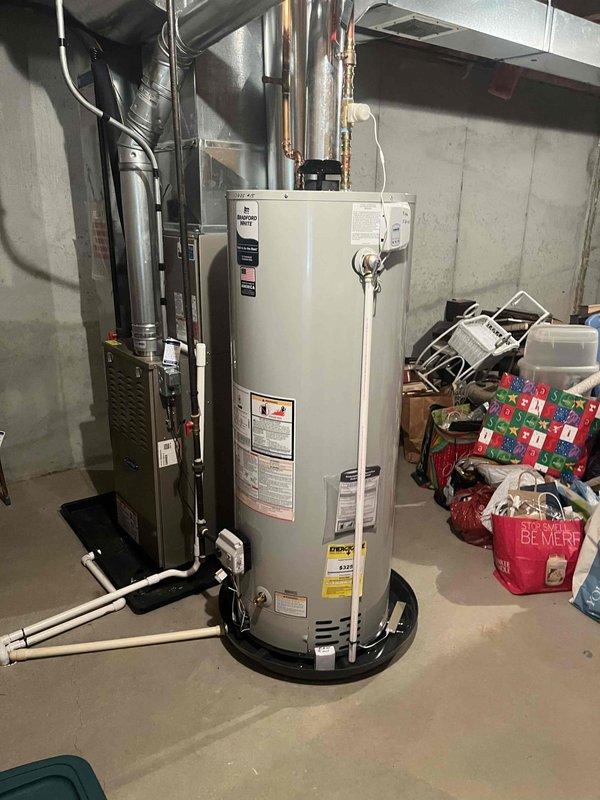 Responded to no hot water call and found 27-year-old Lochinvar water heater completely inoperative. Upon inspection, determined unit had reached end of serviceable life and was beyond economical repair. Documented existing installation with photos showing unit configuration, piping connections, and basement utility room layout for replacement planning purposes.