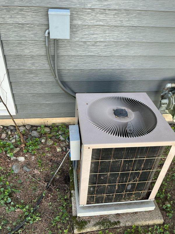 Conducted on-site evaluation of existing residential air conditioning system to provide replacement estimate. Inspected outdoor condensing unit showing signs of age and weathering, documented current installation including electrical disconnect, refrigerant line set routing, and concrete pad placement. Assessed indoor HVAC components including furnace/air handler connections, humidification system integration, and existing ductwork configuration to determine compatibility requirements for new equipment installation.
