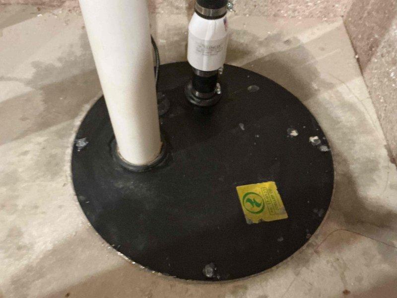 Responded to non-operational sump pump causing water backup in basement. Upon arrival after 6:30 PM, inspected sump pump system with black rubber cover plate and white PVC discharge piping. Evaluated pump mechanism, check valve assembly, and exterior discharge configuration including brass ball valves and weathered piping connections. Restored system to proper working order, eliminating backup condition and ensuring adequate water removal capability.