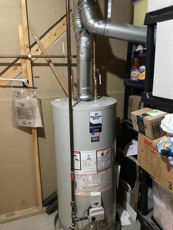 Completed installation of a 40-gallon natural gas Bradford White water heater (Model M240S6BN) with natural draft venting in residential basement utility area. Unit features 40,000 BTU/hr input rating, Category I atmospheric venting with galvanized steel vent pipe and 90-degree elbow exhaust configuration, and meets ANSI Z21.10.1-2019/CSA 4.1-2019 standards with low NOx emissions compliance. Installation verified proper clearances per manufacturer specifications, secured all gas connections, confirmed draft hood assembly, and ensured all safety labels and operational instructions remain visible and intact.