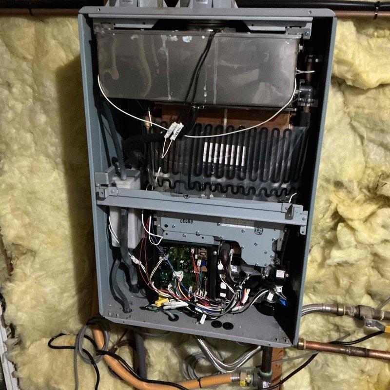 Responded to service call for on-demand tankless water heater experiencing intermittent failure to ignite at specific fixtures while operating normally at others. Performed diagnostic inspection of wall-mounted tankless unit, removing front access panel to examine internal components including heat exchanger, control board, wiring connections, and gas supply lines. Verified proper electrical connections, inspected circuit board for signs of failure, and checked all wire harnesses for loose connections or corrosion. Examined copper piping and gas line connections for restrictions or issues affecting flow sensing. Tested unit operation at multiple fixtures throughout the property to replicate reported intermittent ignition problem. Documented findings with photographs of internal components and installation environment for reference. Homeowner noted unit age unknown, having been in place at least five years prior to current ownership, which may contribute to component wear affecting flow