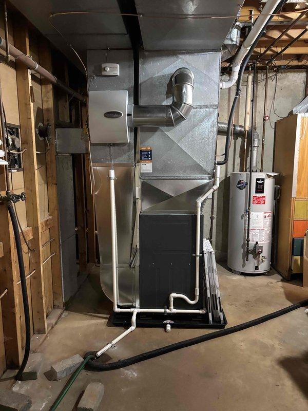 Completed full furnace installation in basement utility area, including new HVAC unit with galvanized metal plenum chamber and metallic ductwork routing. Installed PVC condensate drainage piping, connected all necessary electrical components, and mounted wall-mounted control panel. System tested and verified operational upon completion.